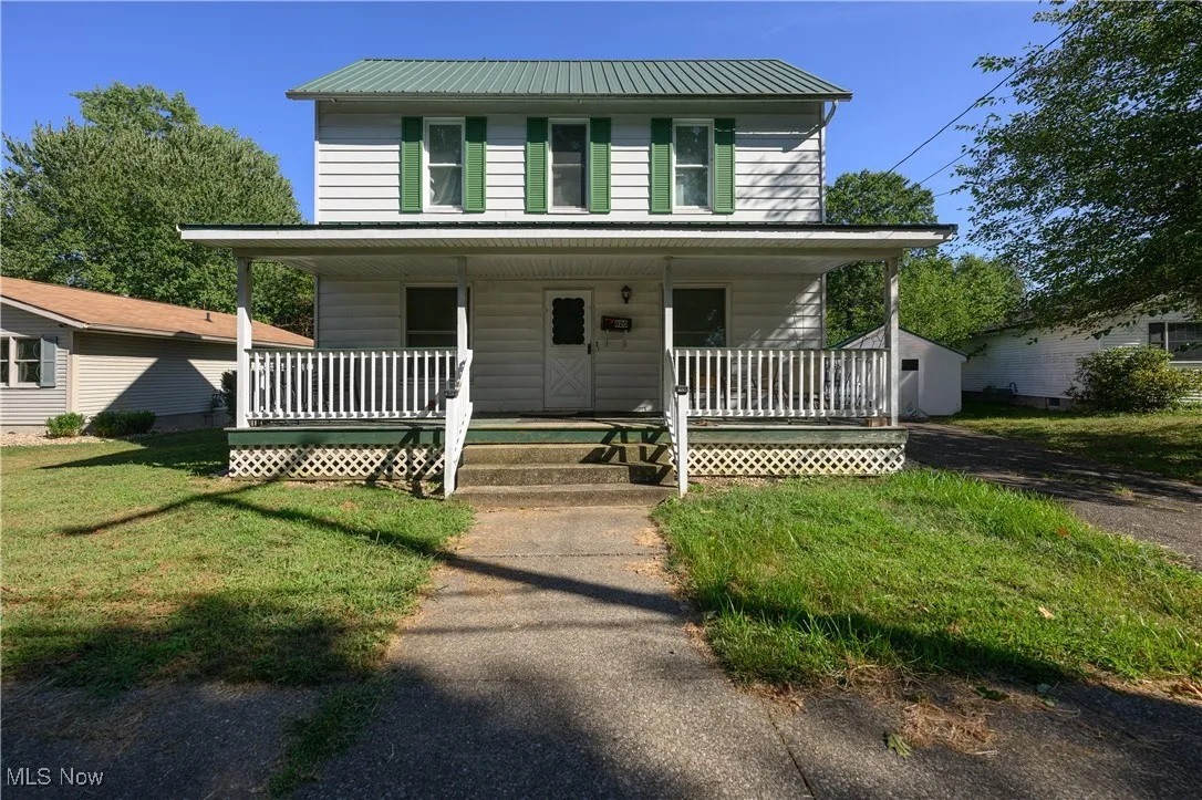 View of front facade featuring covered porch, a front lawn, and a metal roof
