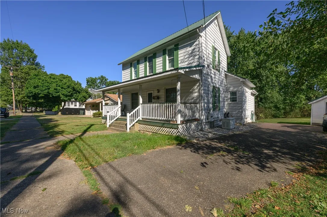 Country-style home featuring covered porch and a front lawn