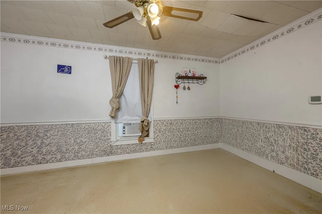 Spare room with a wainscoted wall, ornamental molding, and ceiling fan