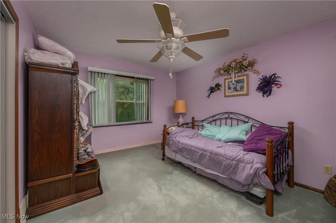 Bedroom with carpet floors, a textured ceiling, and ceiling fan