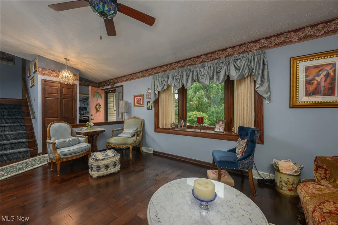 Sitting room featuring stairway, wood-type flooring, a ceiling fan, a chandelier, and a textured ceiling