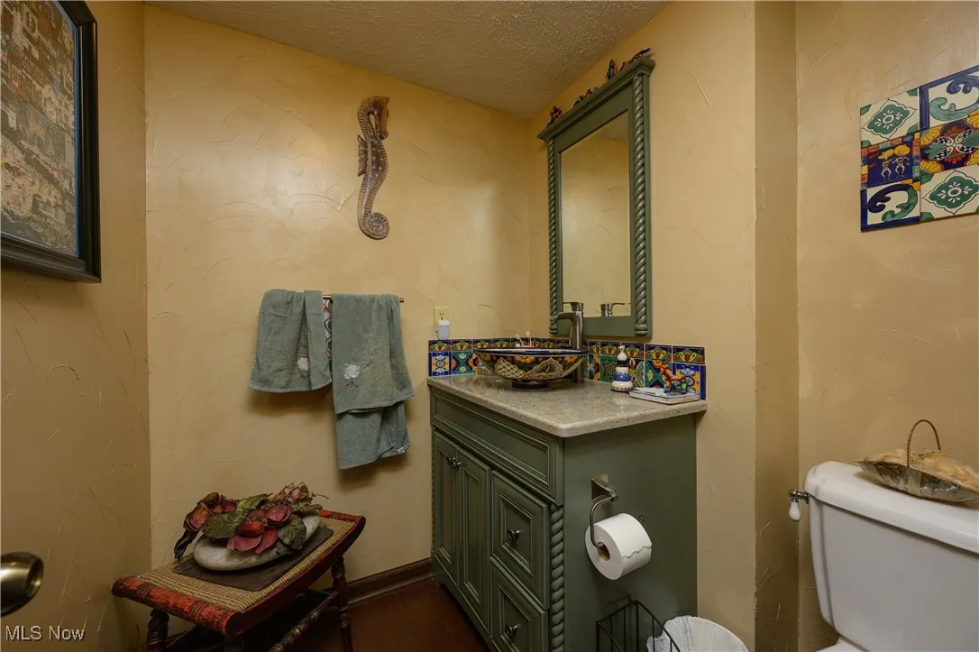 Bathroom with a textured ceiling, a textured wall, and vanity