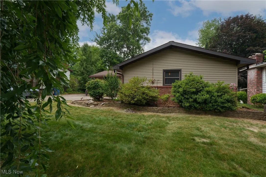 View of side of property with a lawn and brick siding