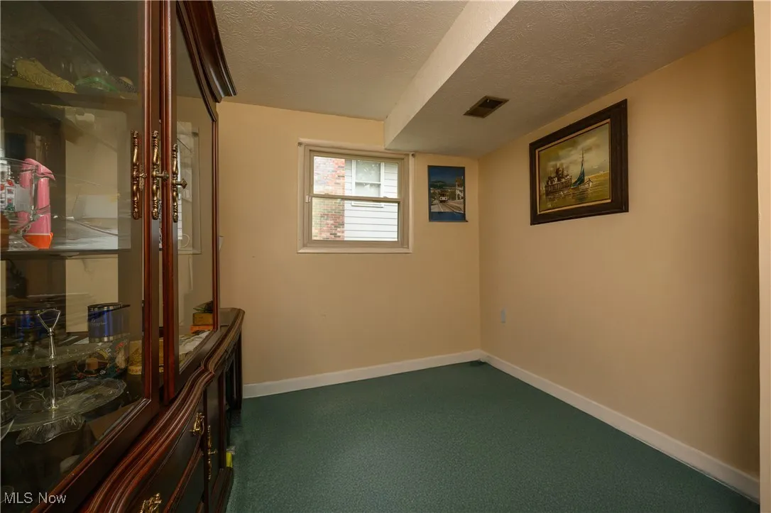 Spare room with a textured ceiling and dark carpet