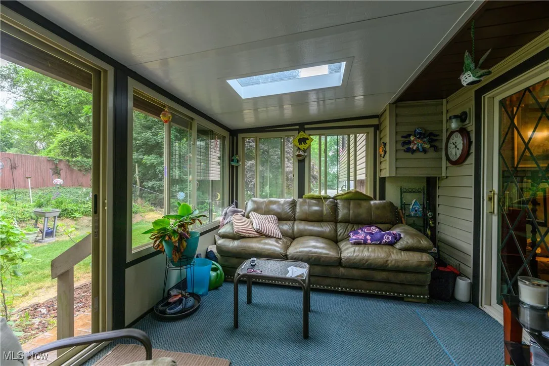 Sunroom / solarium featuring a skylight, lofted ceiling, and an outdoor hangout area