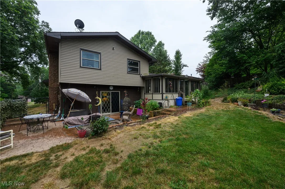 Rear view of property with a sunroom and a patio