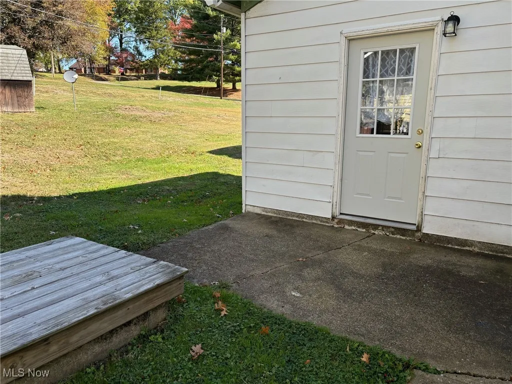 Back doorway to property featuring a yard and a patio