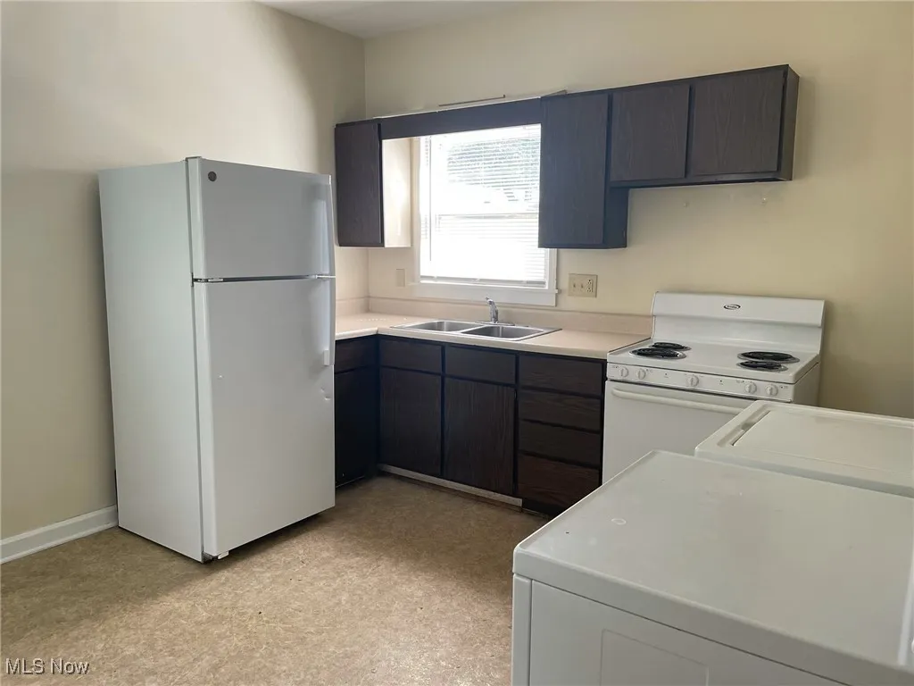 Kitchen with white appliances, light countertops, and washer / dryer