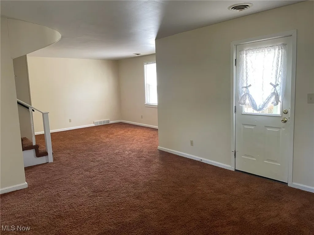 Entrance with dark carpet and stairway