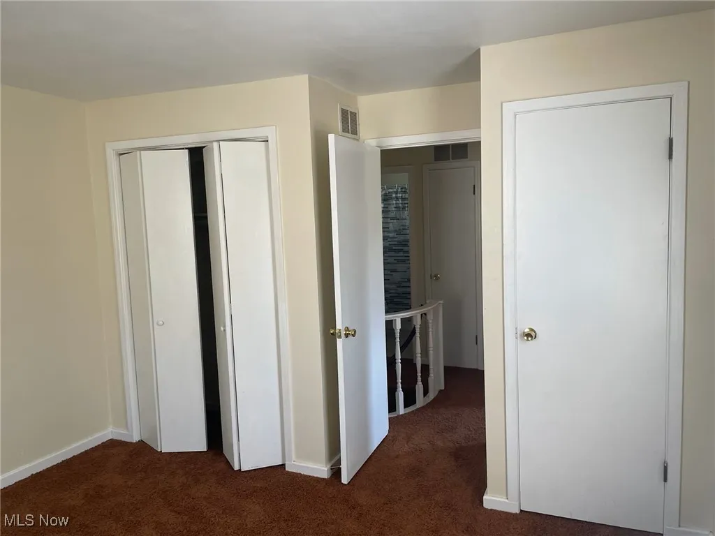 Unfurnished bedroom with dark carpet and a closet