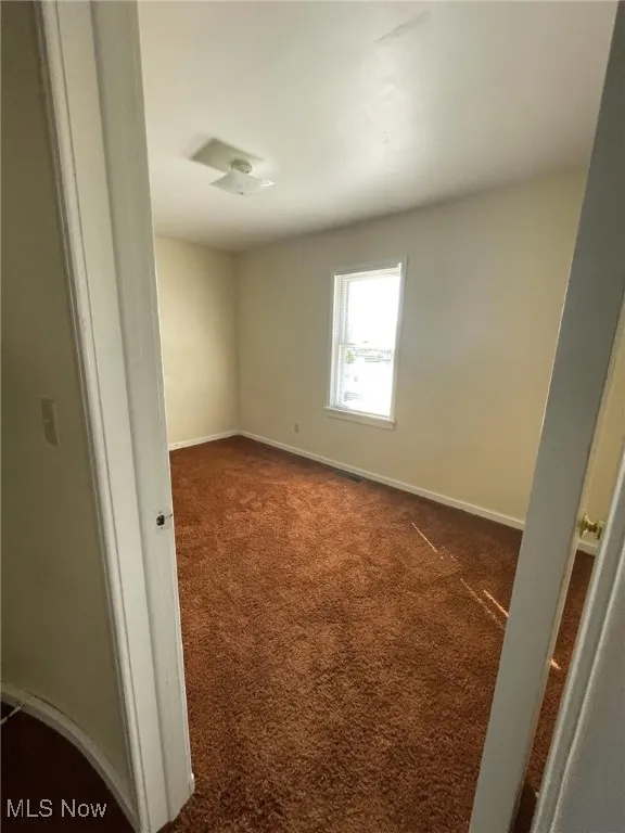 Bedroom featuring dark carpet and baseboards