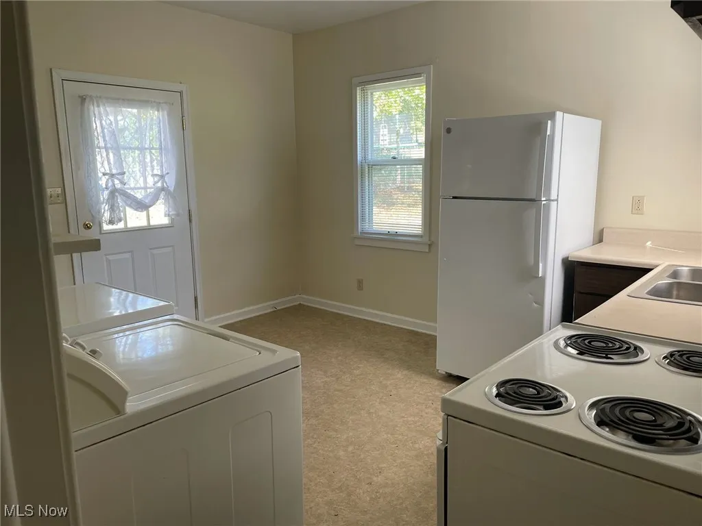 Kitchen featuring white appliances, light countertops, and white cabinetry