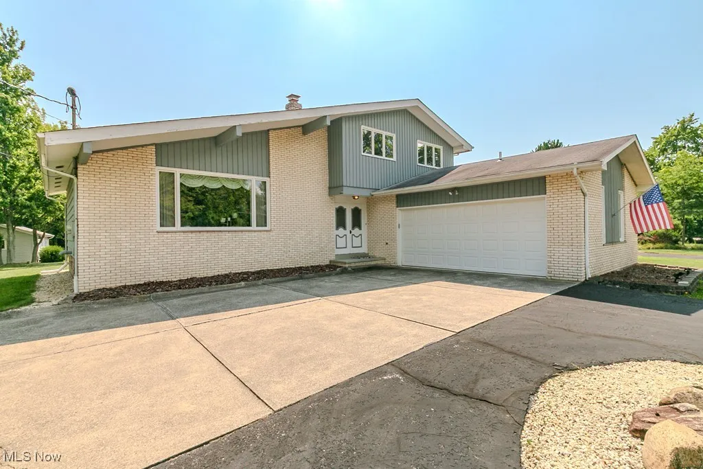 View of front of property featuring concrete driveway, a garage, brick siding, and a chimney