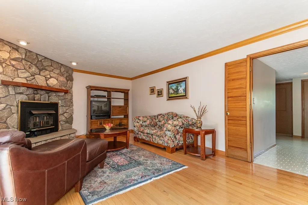 Living room featuring crown molding, light wood-style flooring, a fireplace, and a textured ceiling