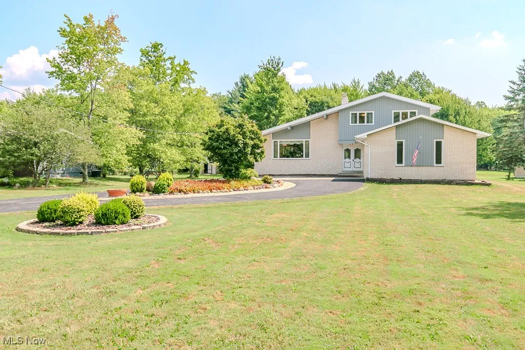 Front of house featuring a yard, driveway, and brick siding