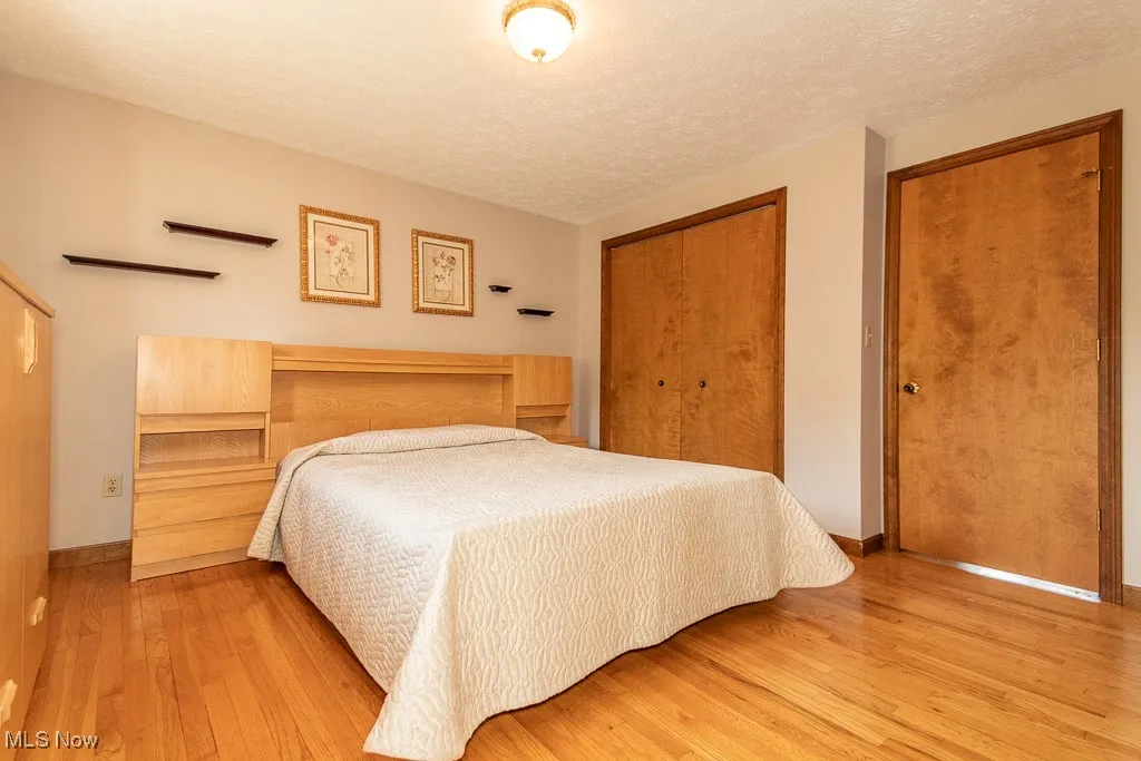 Bedroom featuring a textured ceiling, a closet, and wood finished floors
