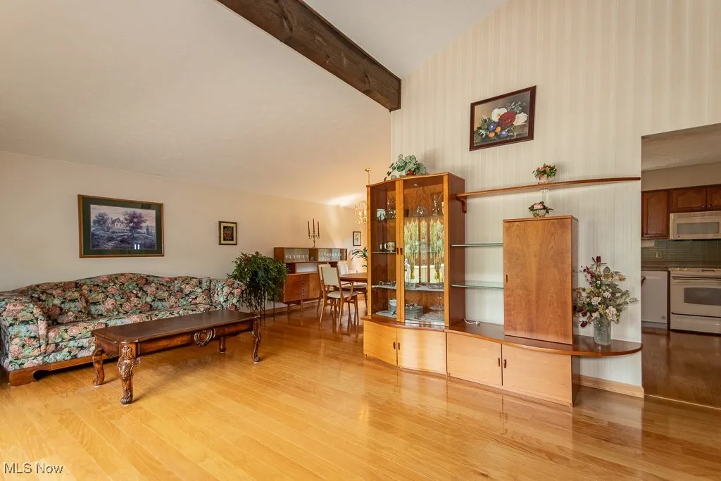 Living area with beamed ceiling, light wood-style floors, and high vaulted ceiling