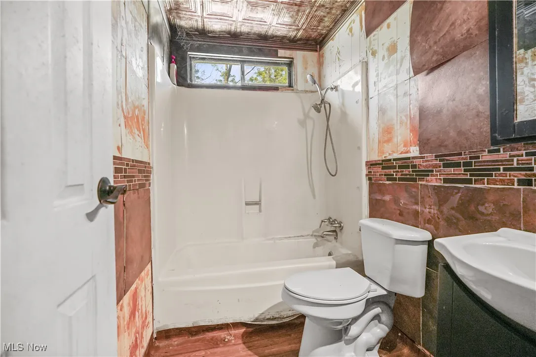 Full bath with shower / bathtub combination, vanity, wood finished floors, an ornate ceiling, and tile walls