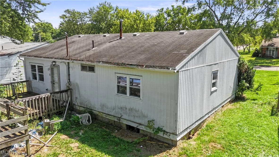 Back of house with roof with shingles and a yard
