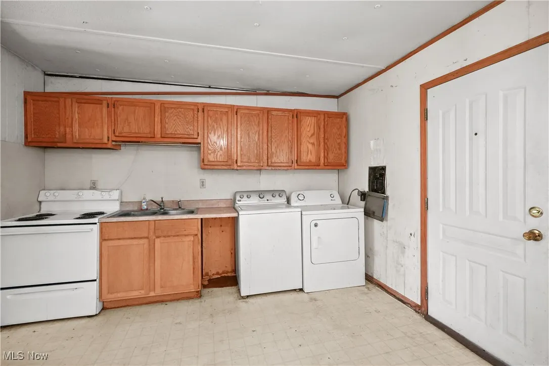 Washroom featuring light flooring, ornamental molding, and washing machine and clothes dryer