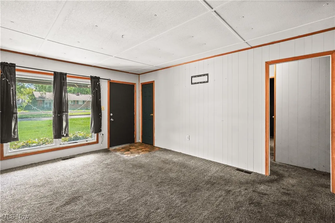 Empty room featuring carpet and wood walls