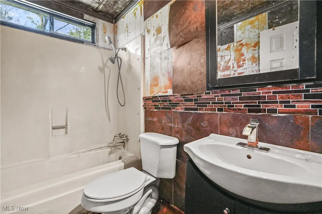 Full bathroom featuring tub / shower combination, vanity, tasteful backsplash, and tile walls