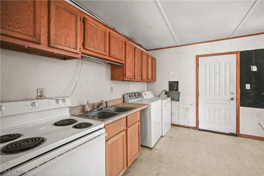 Kitchen featuring white range with electric cooktop, light floors, light countertops, brown cabinetry, and crown molding