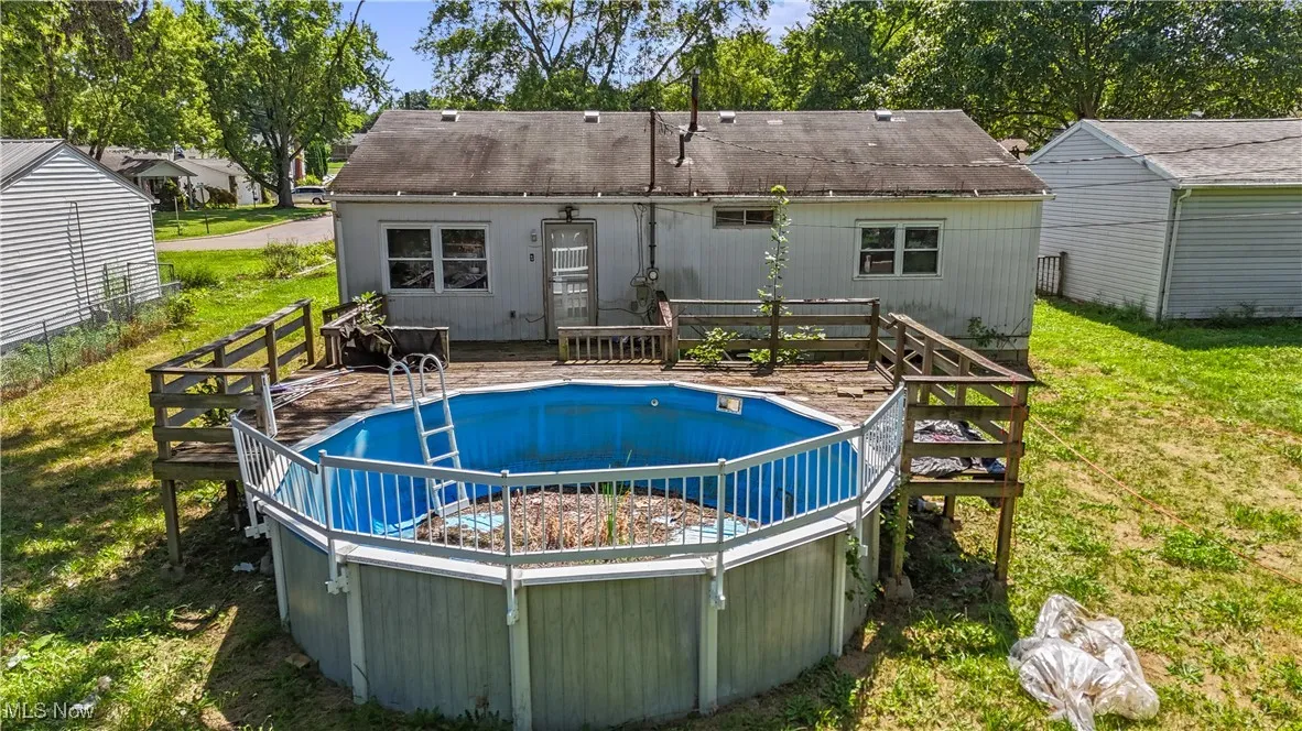 Swimming pool featuring a lawn, a deck, and a patio area