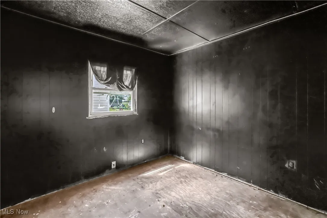 Unfurnished room featuring wooden walls