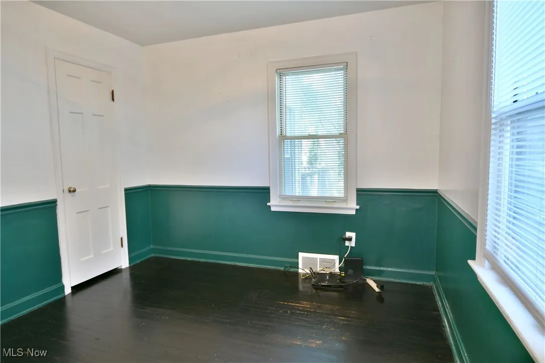 Spare room featuring wainscoting and dark wood finished floors