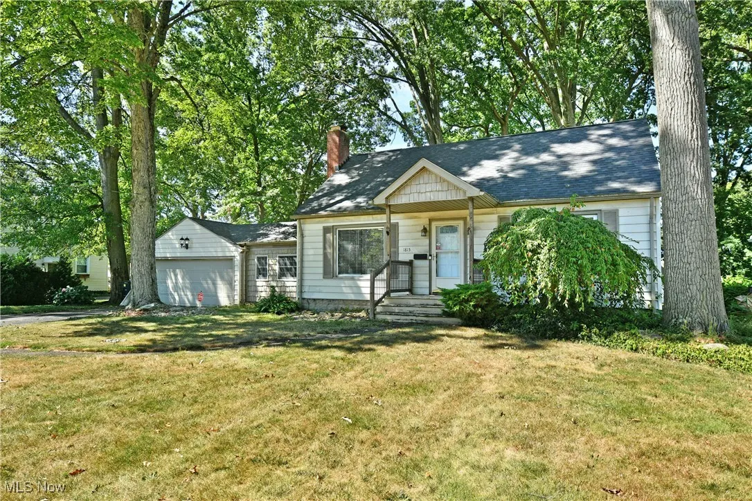 View of front facade with a chimney, a garage, and a front lawn