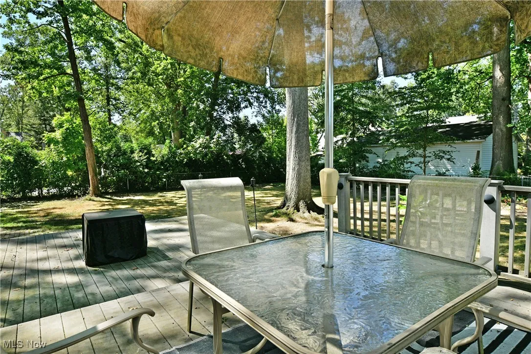Wooden deck featuring outdoor dining area and view of wooded area