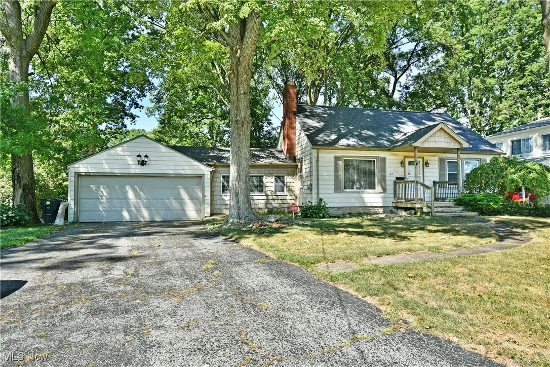 Ranch-style house featuring driveway, a garage, a chimney, a front lawn, and roof with shingles