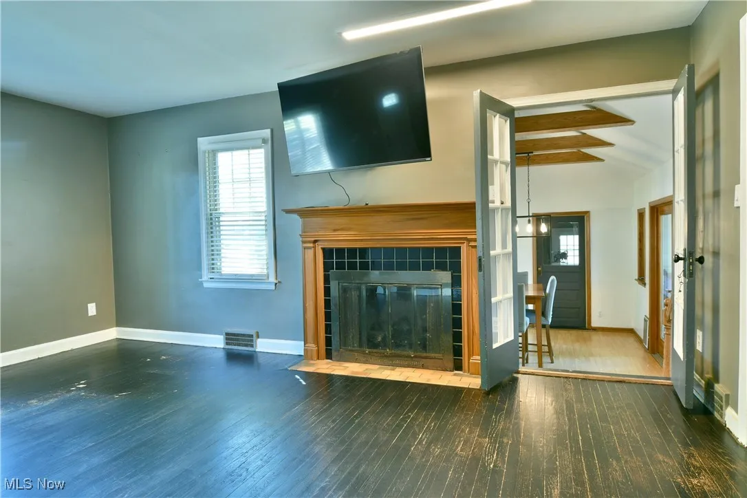 Unfurnished living room with dark wood finished floors, healthy amount of natural light, and a fireplace
