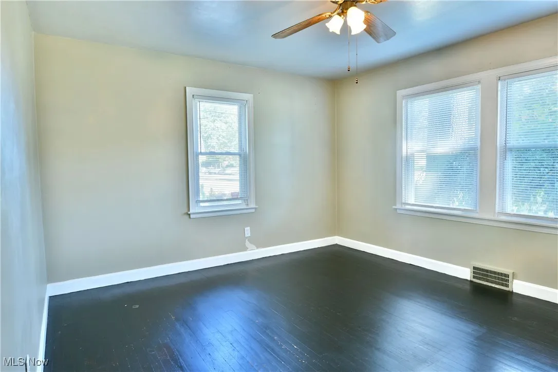 Unfurnished room with dark wood-type flooring and a ceiling fan