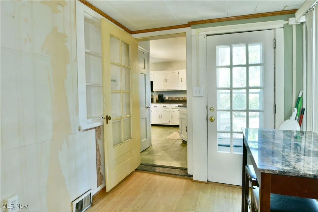 Doorway to outside with wood finished floors and crown molding