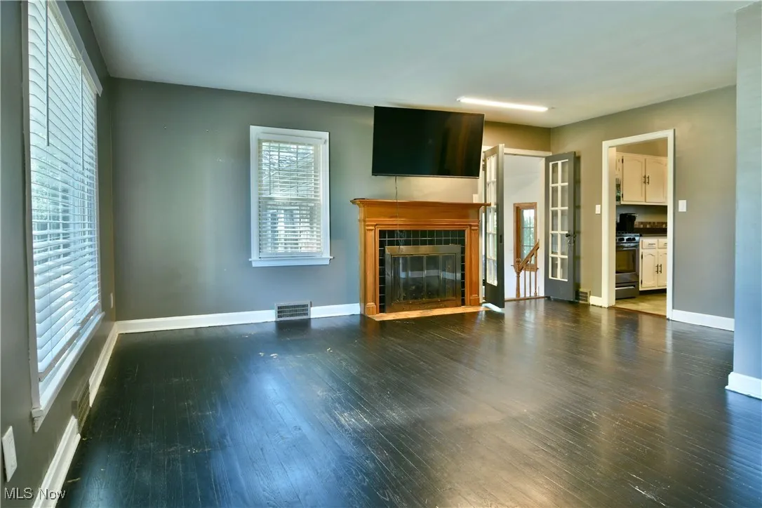 Unfurnished living room featuring dark wood-type flooring and a tile fireplace