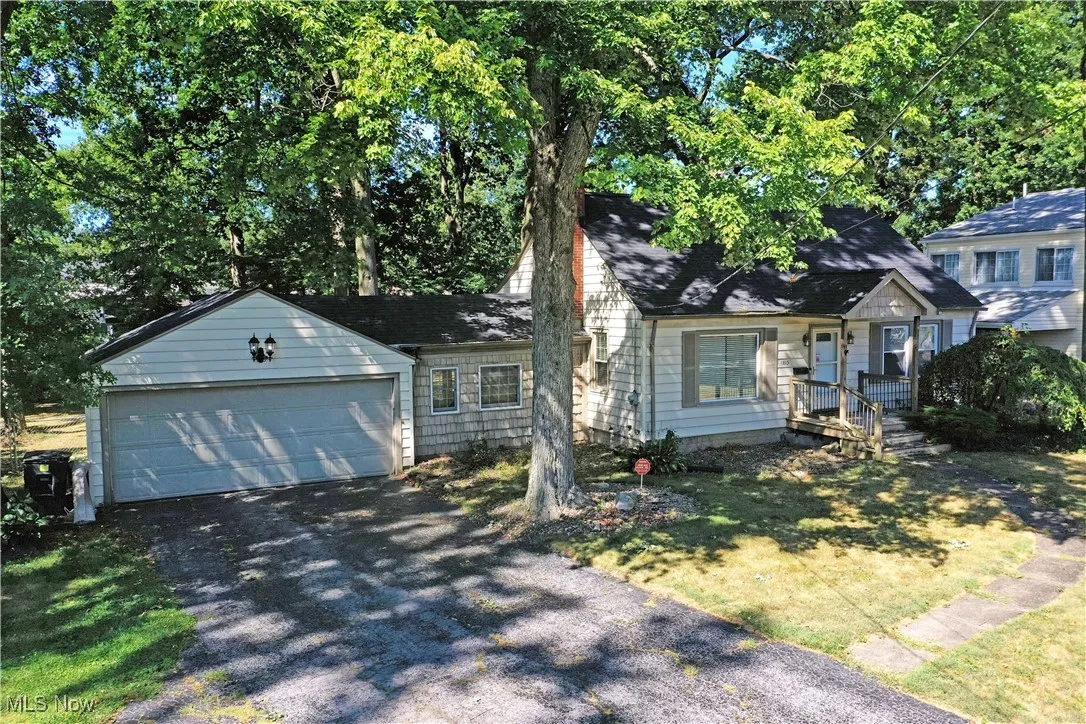 View of front of house with driveway, an attached garage, a porch, and a front lawn