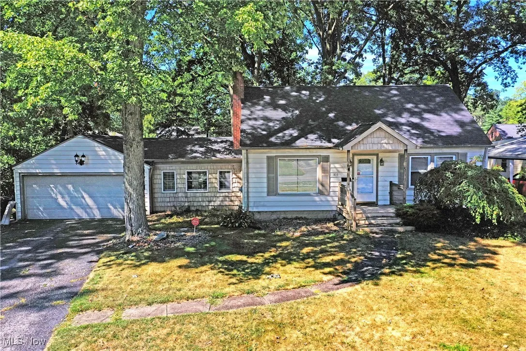 View of front of property with driveway, a front lawn, a garage, and roof with shingles
