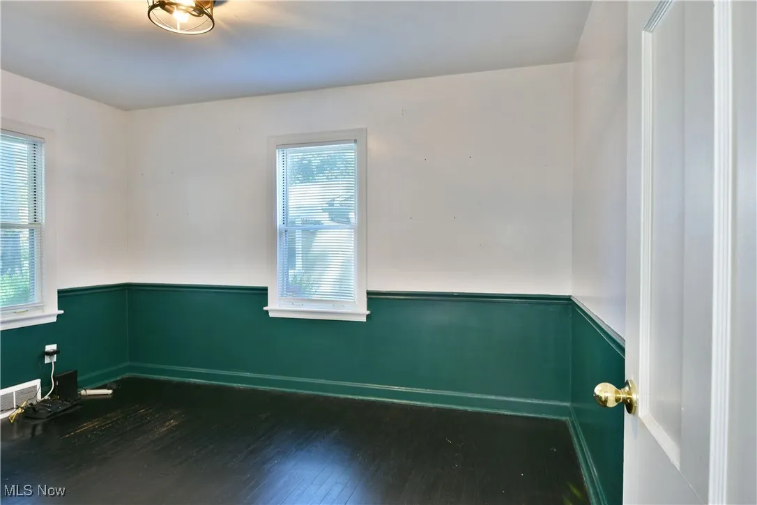 Unfurnished room with a wainscoted wall and dark wood finished floors