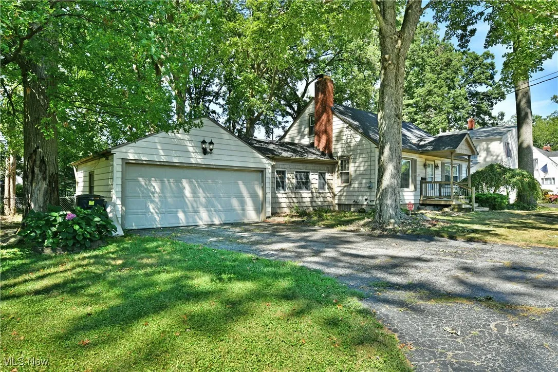 View of front of home with asphalt driveway, a chimney, a garage, and a front lawn
