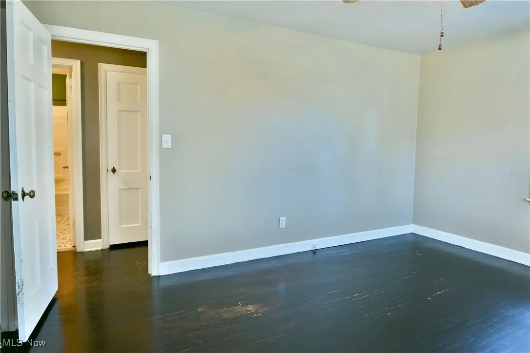 Empty room with dark wood-type flooring and a ceiling fan