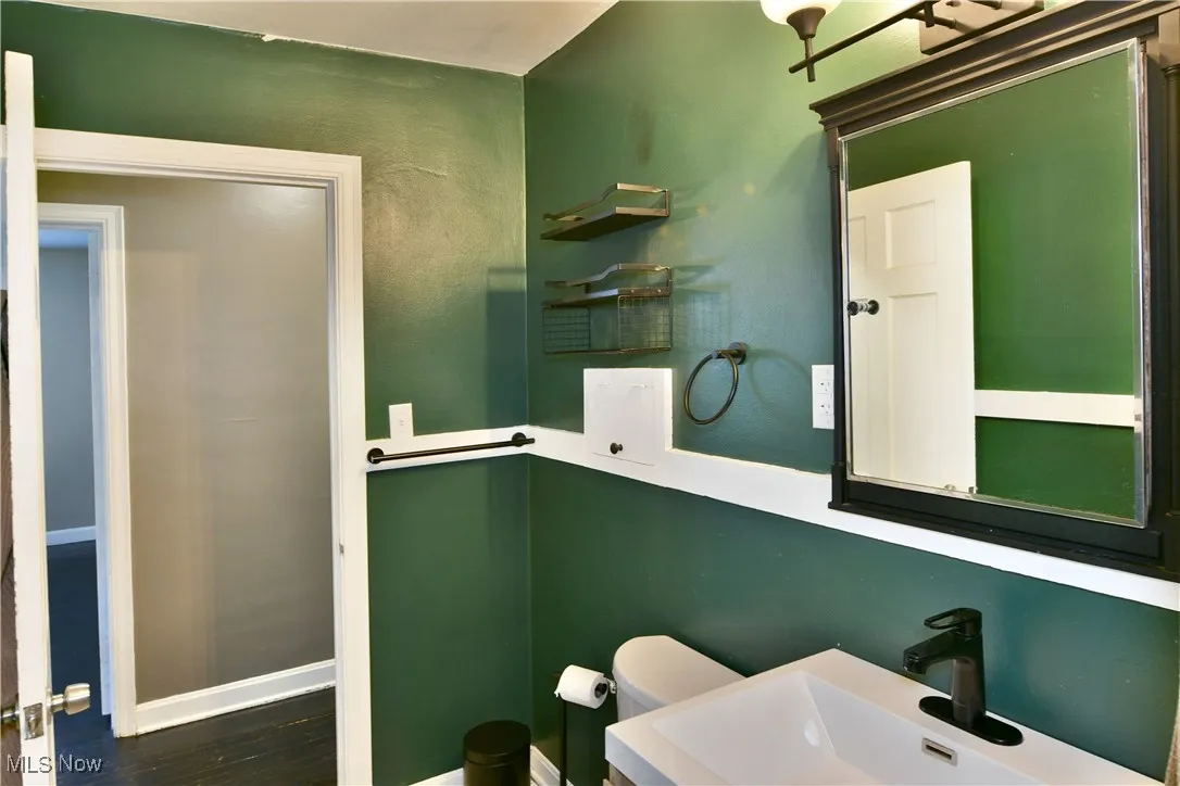 Half bath with toilet and dark wood-type flooring