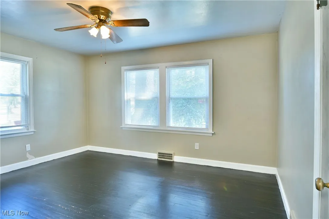 Spare room with dark wood finished floors and a ceiling fan