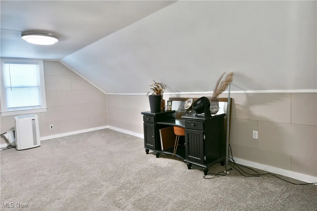 Bonus room with carpet flooring and vaulted ceiling