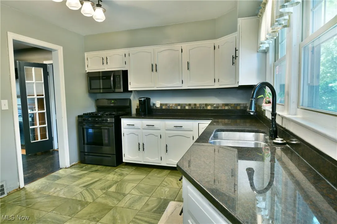 Kitchen with white cabinets, black gas range oven, and dark stone countertops