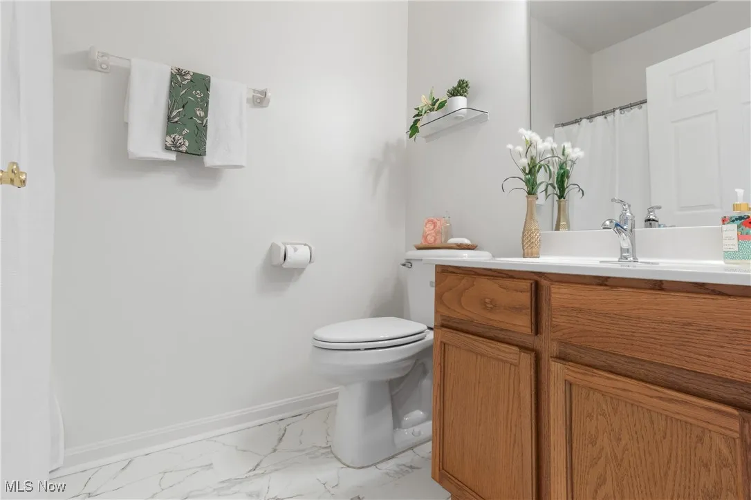Full bath with vanity and light marble finish flooring