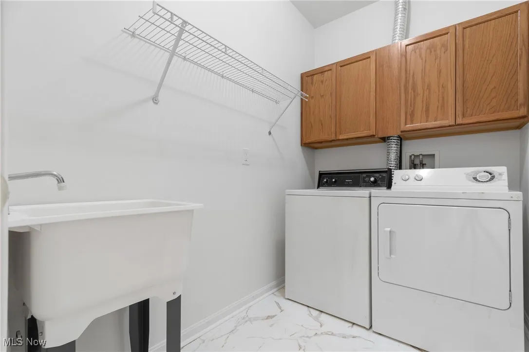 Laundry area featuring light marble finish floors, cabinet space, and independent washer and dryer