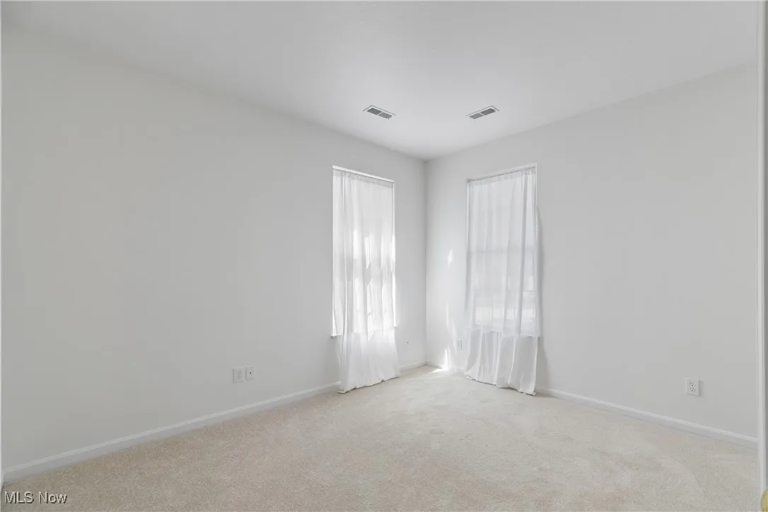 Empty room with light colored carpet and baseboards