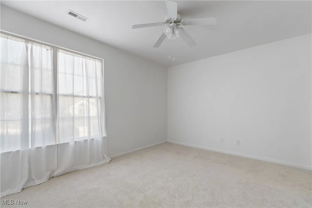 Empty room with light carpet and ceiling fan